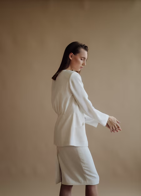 Model in an ivory tailored evening look against a warm beige backdrop