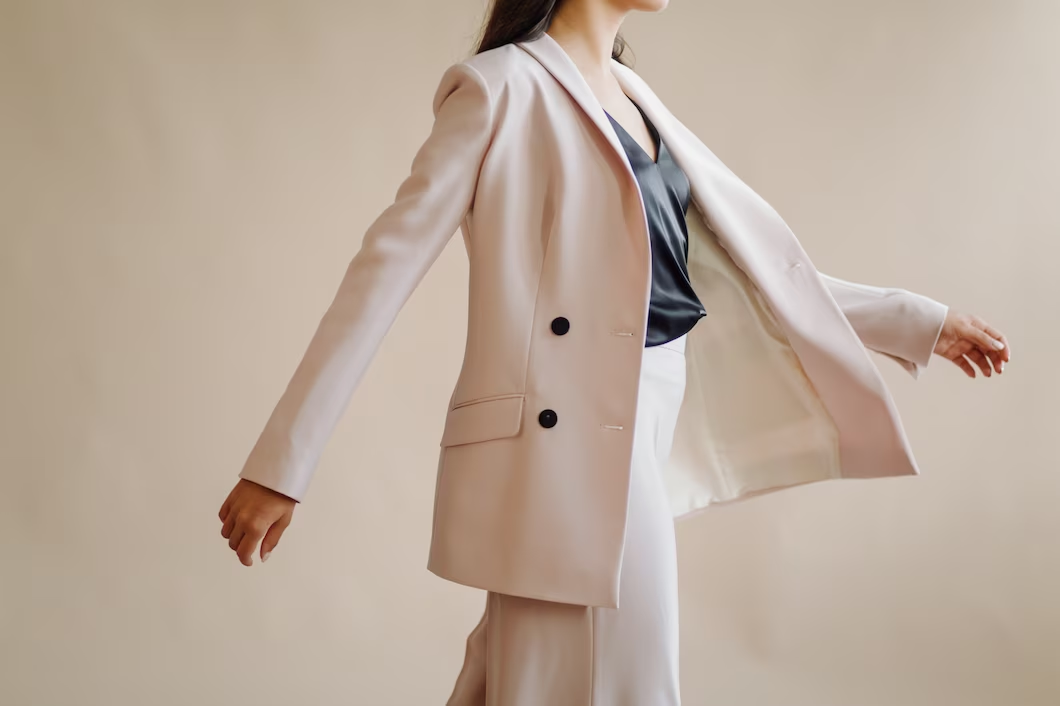 Model in a blush pink tailored blazer and satin top mid-stride