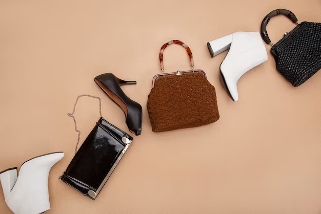 Flat lay of a tortoiseshell-handle handbag, patent clutch and white boots on peach