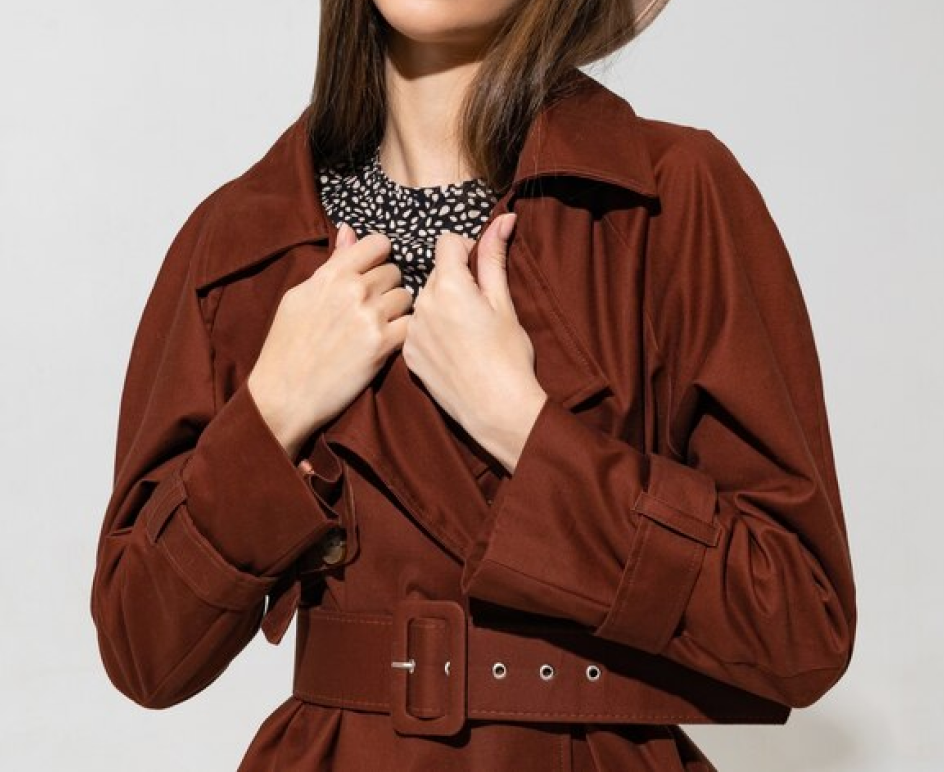 Model in a rust-brown belted coat over a printed blouse